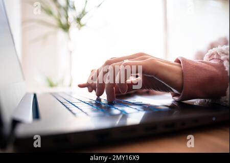 Low angle closeup view of female hands typing and using laptop computer. Stock Photo