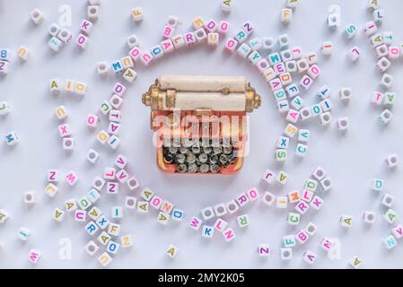 Alphabet beads with miniature typewriter on white background. Stock Photo