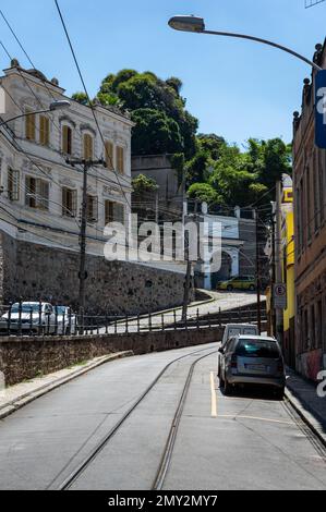 The uphill Almirante Alexandrino street surrounded by old buildings saw from Largo dos Guimaraes tram stop under summer afternoon sunny clear blue sky Stock Photo