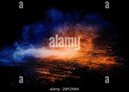 Orange blue  powder explosion on black background.Orange blue color dust splashing. Stock Photo