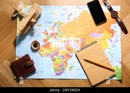 Flat lay composition with world map and different items on wooden background. Trip planning Stock Photo