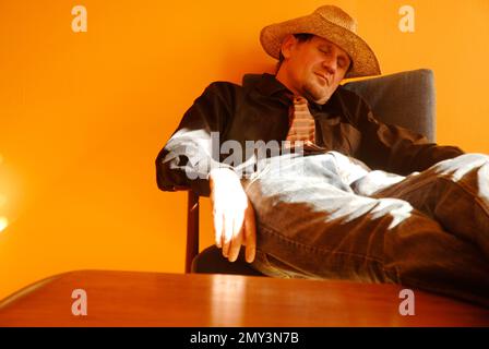 Young man in a straw hat fell asleep on a chair Stock Photo
