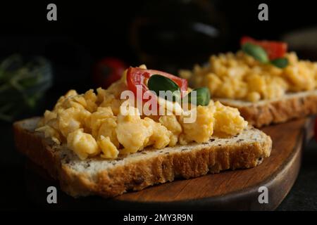 Tasty scrambled egg sandwiches served on wooden board, closeup Stock Photo