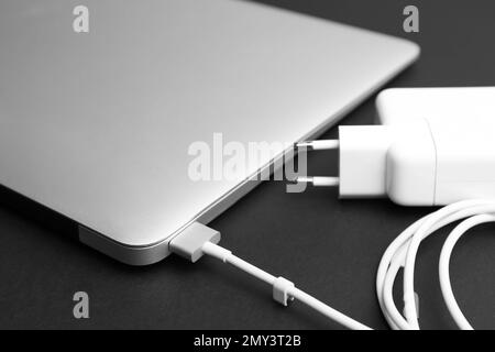 Laptop and charger on black background, closeup. Modern technology Stock Photo