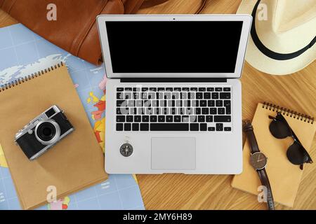 Flat lay composition with laptop and different items on wooden table. Trip planning Stock Photo