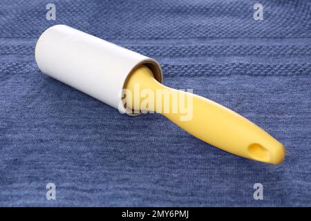 New lint roller with yellow handle on blue fabric Stock Photo