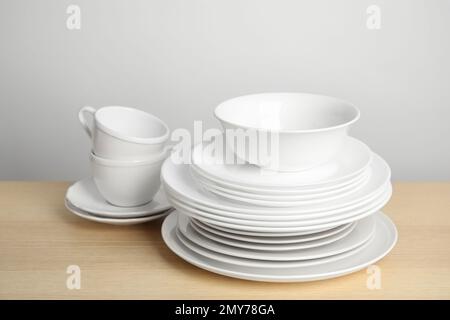 Clean plates, bowl and cups on wooden table against white background Stock Photo