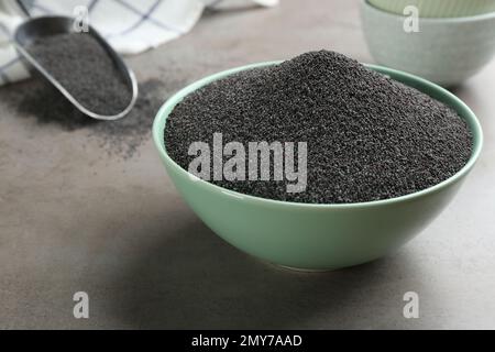 Poppy seeds in bowl on grey table Stock Photo