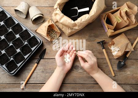 Woman preparing vegetable seeds for planting at wooden table, closeup Stock Photo