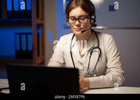 Doctor with headset during a video consult with a patient during night shift. Telemedicine concept. Copy space Stock Photo