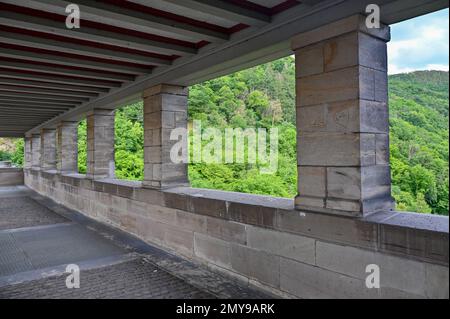 Columns on the pedestrian path on the Edersee dam in Germany with a view of the green forest Stock Photo