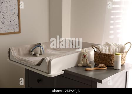 Chest of drawers with changing pad and tray in nursery. Baby room interior design Stock Photo