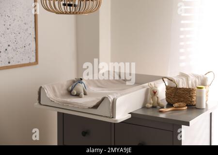 Chest of drawers with changing pad and tray in nursery. Baby room interior design Stock Photo