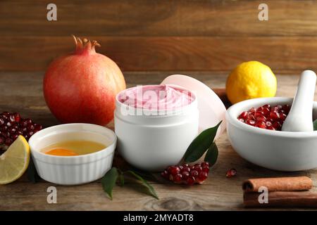 Natural homemade mask, pomegranate and ingredients on wooden table Stock Photo
