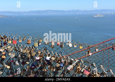 Close up of many love lock padlocks placed by tourists on a chain link fence above the Golden Gate Bridge with the San Francisco bay in the background Stock Photo