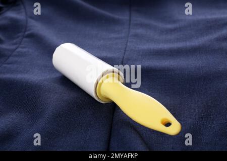 New lint roller with yellow handle on blue jacket Stock Photo