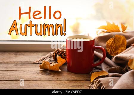 Hello Autumn card. Cup of hot drink, golden leaves and scarf on wooden windowsill Stock Photo