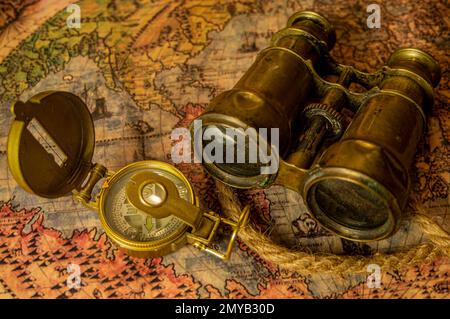 Antique adventure scroll background on adventurer table. Binoculars, parchment, rope and compass on table. Stock Photo