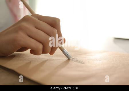 Woman correcting picture on paper with pencil eraser, closeup Stock Photo