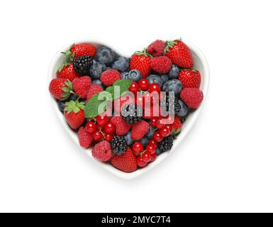 Mix of berries in heart shaped bowl isolated on white, top view Stock Photo