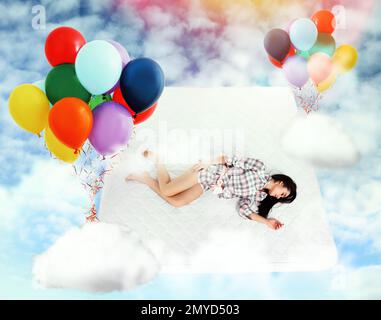 Sweet dreams. Bright cloudy sky with air balloons around sleeping young woman Stock Photo