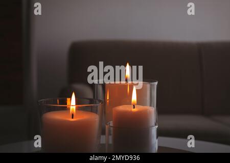 Burning candles in glass holders indoors, closeup Stock Photo