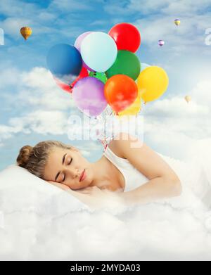 Young beautiful woman sleeping in bed. Bright air balloons in blue cloudy sky - sweet dreams Stock Photo