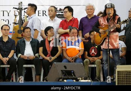 Philippine President Rodrigo Duterte, second from left, looks as Filipino  folk singer Freddie Aguilar sings during the solidarity dinner with the poor  event at a slum area in Manila, Philippines on Thursday, June 30, 2016.  Duterte was sworn in Thursday as ...