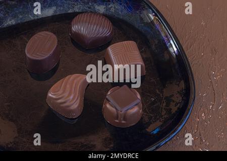 Variety of assorted flavors chocolate candies on black plate Stock Photo