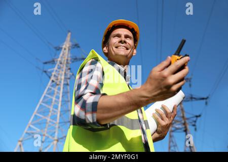 Professional electrician with portable radio station near high voltage tower Stock Photo