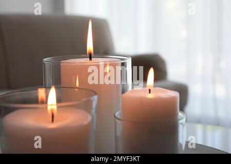 Burning candles in glass holders indoors, closeup Stock Photo