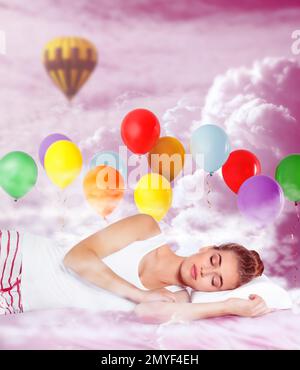 Sweet dreams. Pink cloudy sky with bright air balloons around sleeping young woman Stock Photo