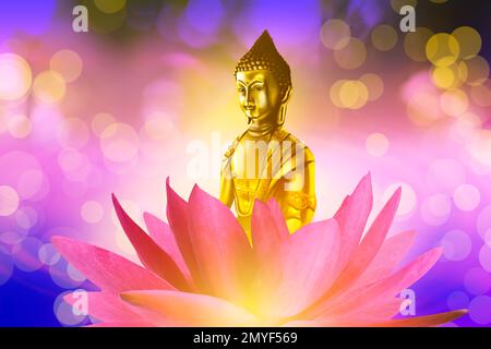 Buddha figure in lotus flower on bright background, bokeh effect Stock Photo
