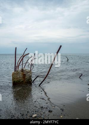 Reinforced concrete sticking out of the water. Remains of the structure. Abandoned. Armature at sea. A pile driven into the bottom of the sea. ruined Stock Photo