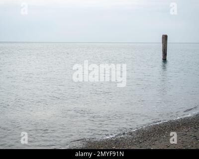 Reinforced concrete pile sticking out of the water. Remains of an old bridge in the sea. Ruined pier. Abandoned. Armature at sea. Destroyed building. Stock Photo