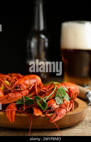 Delicious red boiled crayfishes and beer on wooden table, closeup Stock Photo
