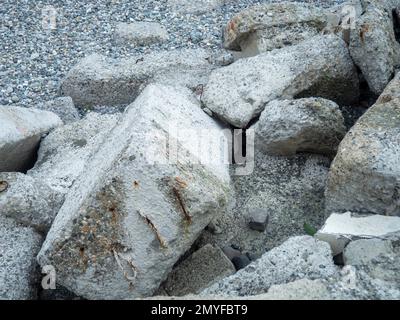 A pile of broken concrete. Cement lumps. Building material on the seashore. Reinforced concrete Stock Photo