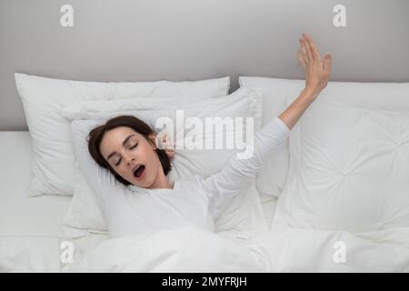 Beauiful young woman stretching in bed after waking up Stock Photo