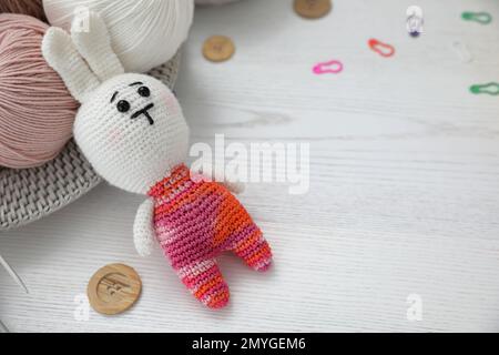 Crocheted bunny and threads on white wooden table. Engaging in hobby Stock Photo