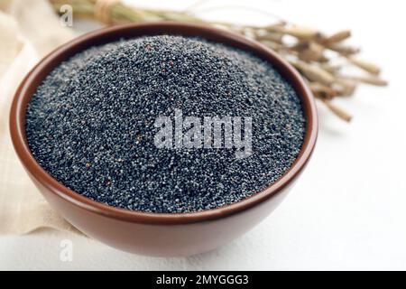 Poppy seeds in bowl on white table Stock Photo