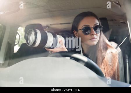 Private detective with camera spying from car Stock Photo