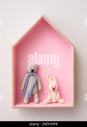 Stylish house shaped shelf with toys on white wall. Baby room interior design Stock Photo