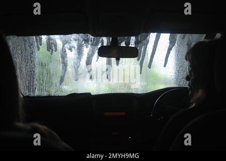 View from inside a car as it goes through an automatic car wash, wet windscreen. Stock Photo