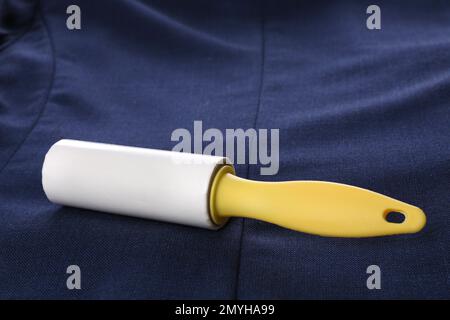 New lint roller with yellow handle on blue jacket Stock Photo