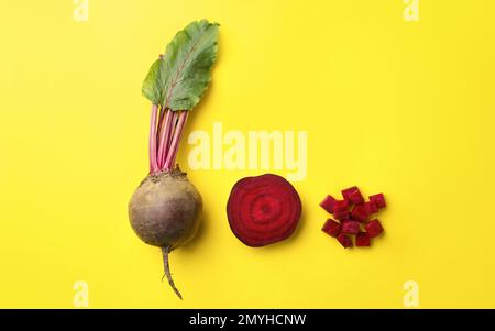 Whole and cut fresh red beets on yellow background, flat lay Stock Photo