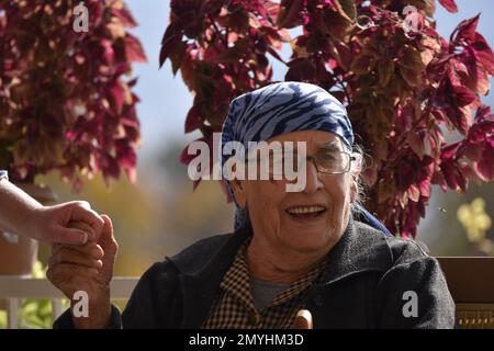 An elderly woman expressing joy at the visit of her young friend, with whom she is holding hands. Stock Photo