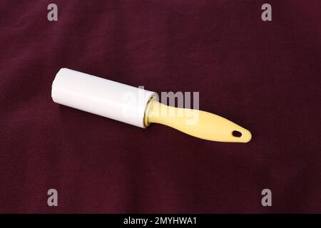 New lint roller with yellow handle on red fabric Stock Photo
