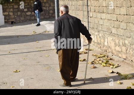 Elderly man with cane walks down the street Stock Photo - Alamy