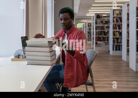 African American male university teacher preparing for online lecture in library Stock Photo