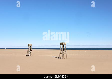 Two wooden structures stand alone on a barren stretch of beach. Stock Photo
